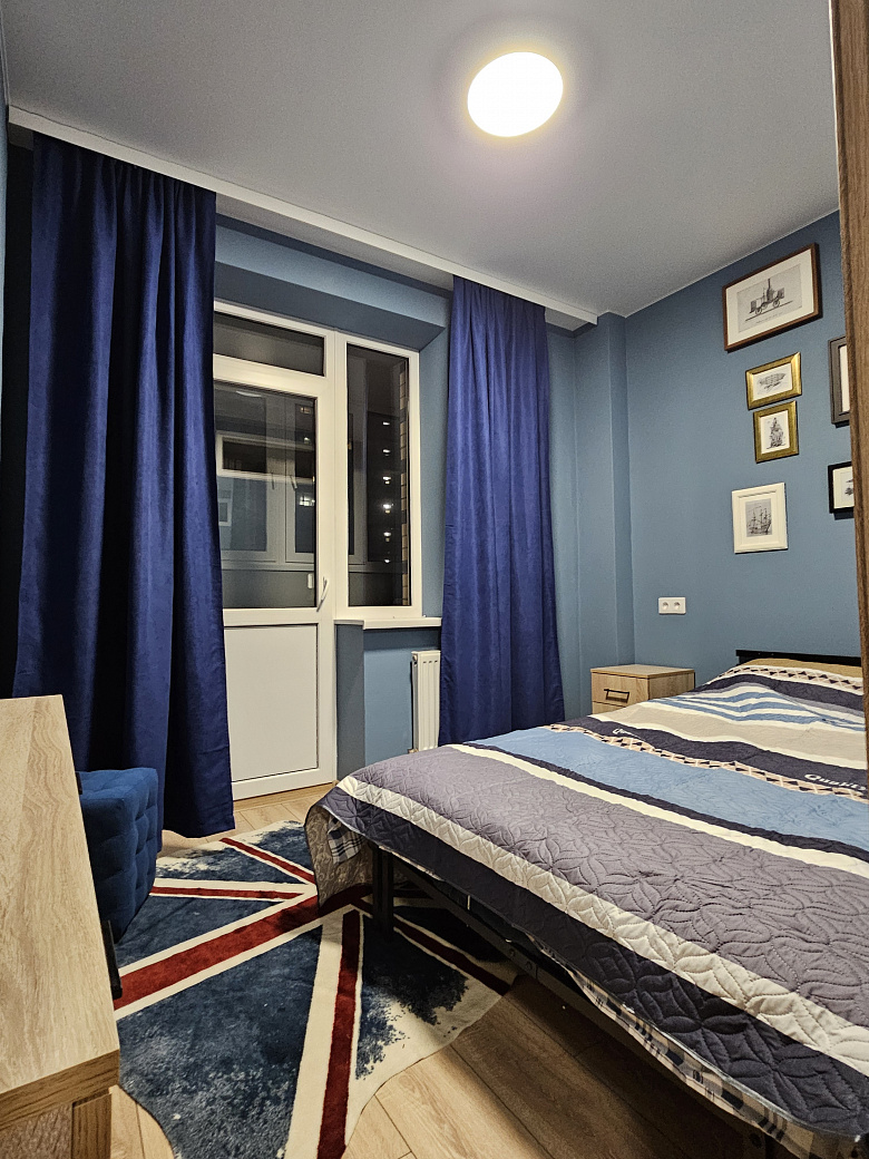 фото:Кровать шириной 140 см, лоджия шириной 130 см, утеплена, там стоит рабочий стол 120 см шириной, шкафы навесные над столом для хранения и стул