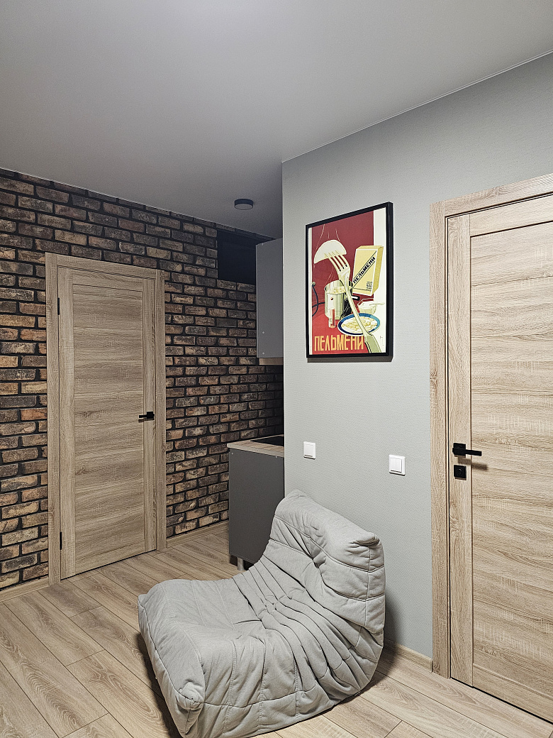 фото:Слева от входной двери (справа на фото) гардеробная с гладильной доской, справа (дверь около картины с пельменями) ванная комната. Кухня поделега на 2 зоны, справа зона готовки, слева зона столовой с телевизором, в кирпичной стене две двери - вход в две раздельные спальни