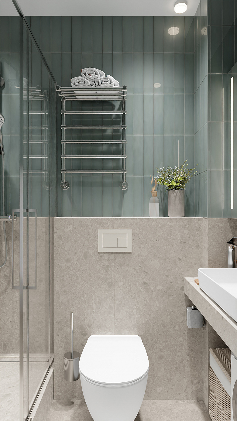 фото:Современная ванная в минималистичном стиле: сочетание серо-бежевой плитки «под камень» в нижней части и спокойной бирюзовой кафельной кладки вверху. Центральные элементы — подвесной унитаз, лаконичная раковина на столешнице, стеклянная душевая кабина. Акценты: металлический полотенцесушитель, декоративная ваза с сухоцветами, стильный ёршик в хромированном держателе. Чистые линии, нейтральная палитра и функциональные детали создают ощущение порядка и свежести