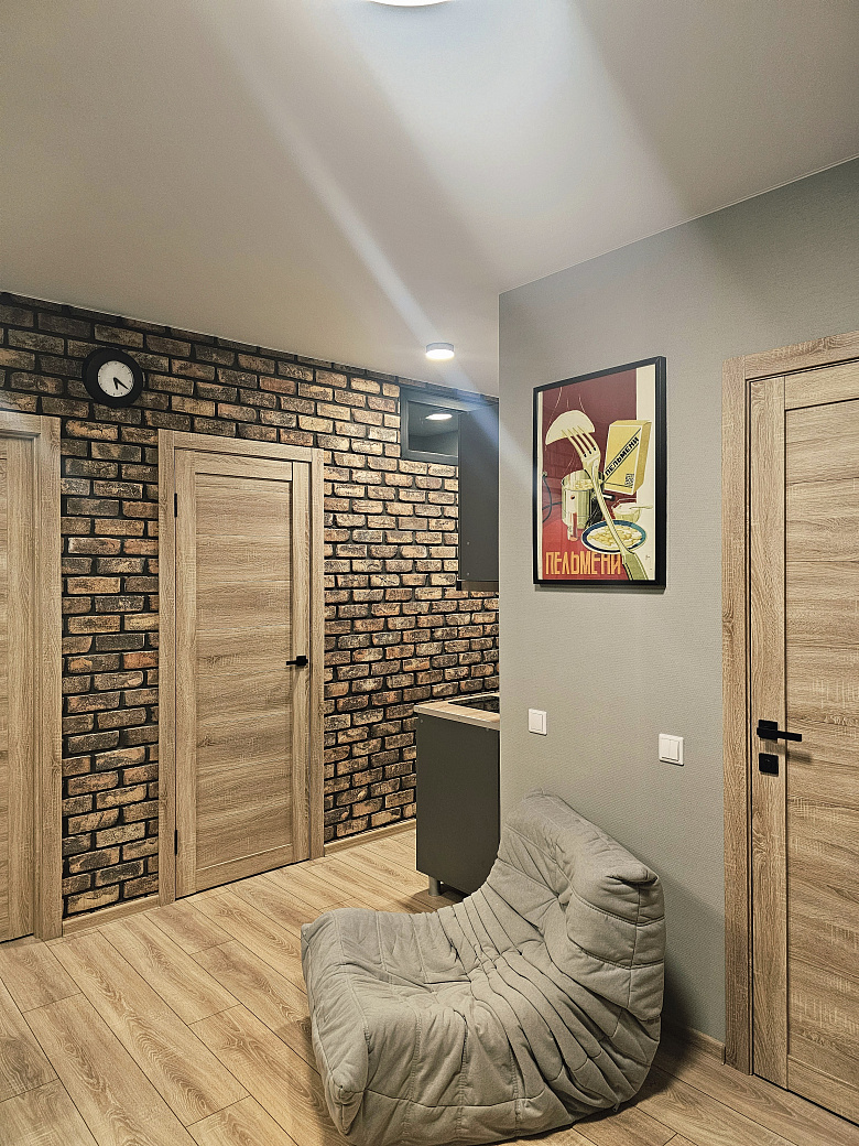 фото:Слева от входной двери (справа на фото) гардеробная с гладильной доской, справа (дверь около картины с пельменями) ванная комната. Кухня поделега на 2 зоны, справа зона готовки, слева зона столовой с телевизором, в кирпичной стене две двери - вход в две раздельные спальни