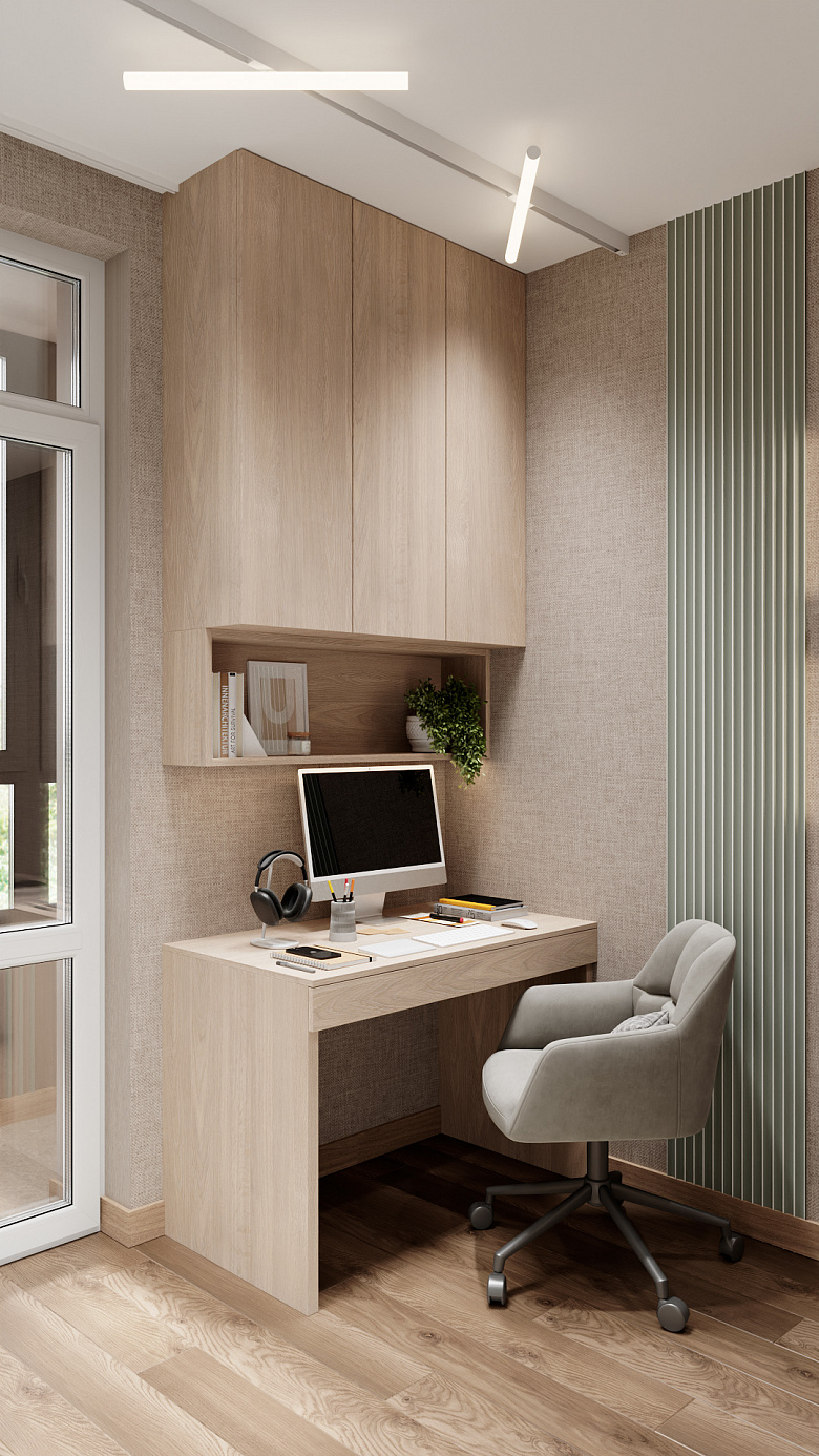 фото:Компактный рабочий уголок в светлых древесных тонах. Навесной шкаф с открытой полкой для книг и декора, лаконичный стол с минималистичной организацией, эргономичное серое кресло на колёсах. Акцент — вертикальная панель с рифлёной текстурой в приглушённом зелёном оттенке. Естественный свет из окна, современное потолочное освещение. Чистые линии, функциональность, уют