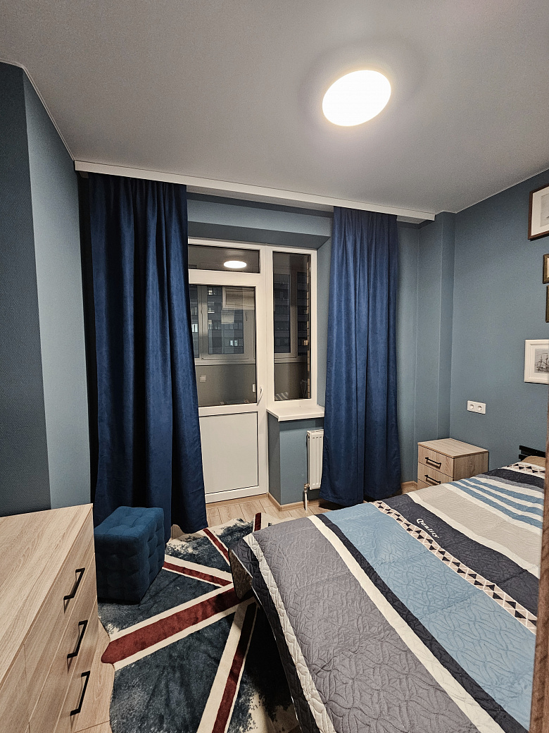 фото:Кровать шириной 140 см, лоджия шириной 130 см, утеплена, там стоит рабочий стол 120 см шириной, шкафы навесные над столом для хранения и стул