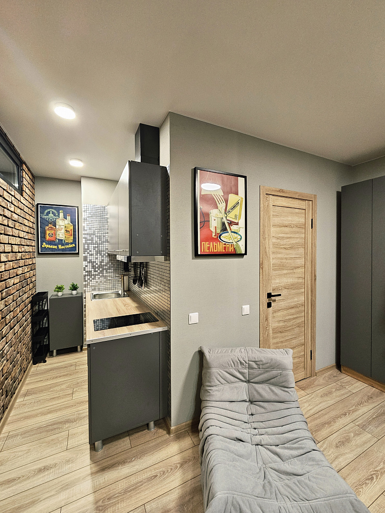 фото:Слева от входной двери (справа на фото) гардеробная с гладильной доской, справа (дверь около картины с пельменями) ванная комната. Кухня поделега на 2 зоны, справа зона готовки, слева зона столовой с телевизором, в кирпичной стене две двери - вход в две раздельные спальни