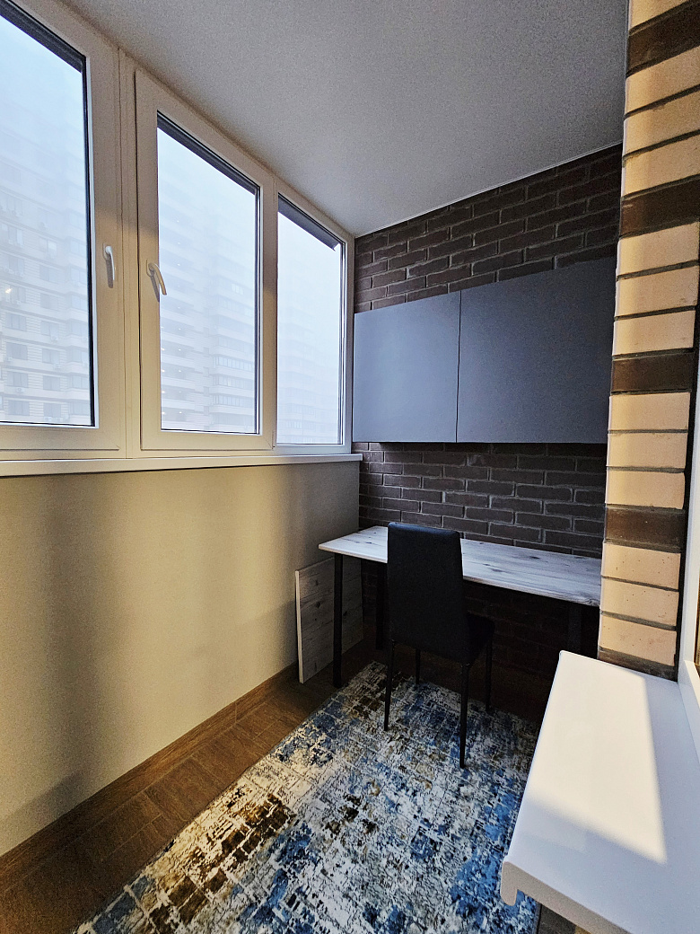 фото:Кровать шириной 140 см, лоджия шириной 130 см, утеплена, там стоит рабочий стол 120 см шириной, шкафы навесные над столом для хранения и стул